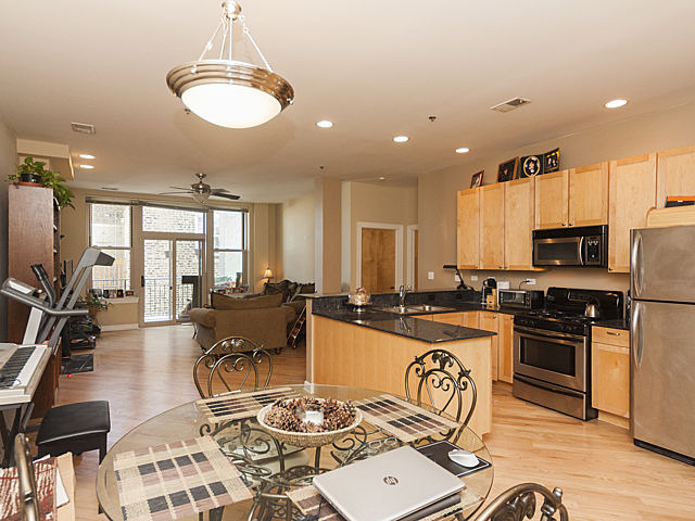 3113 West Lawrence Avenue, Unit D302 Chicago, IL 60625 - Photo 8 of 16 a kitchen with stainless steel appliances granite countertop a stove top oven a sink a dining table and chairs with wooden floor