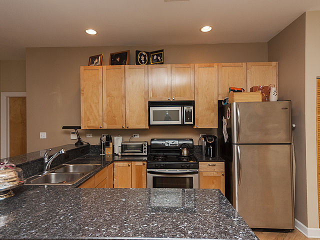 3113 West Lawrence Avenue, Unit D302 Chicago, IL 60625 - Photo 10 of 16 a kitchen with kitchen island a counter top space a sink a refrigerator and a stove top oven
