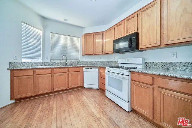 a kitchen with stainless steel appliances granite countertop wooden cabinets granite counter tops and a hard wood floors