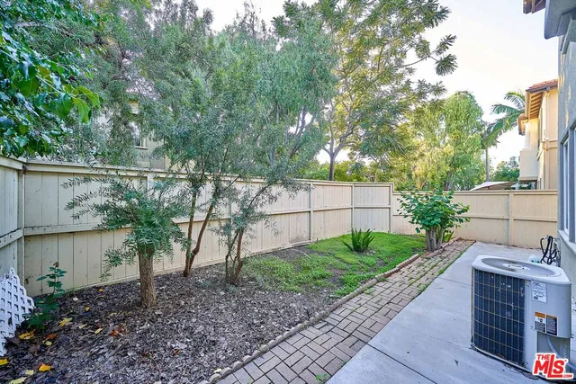 a view of a backyard with plants and large trees