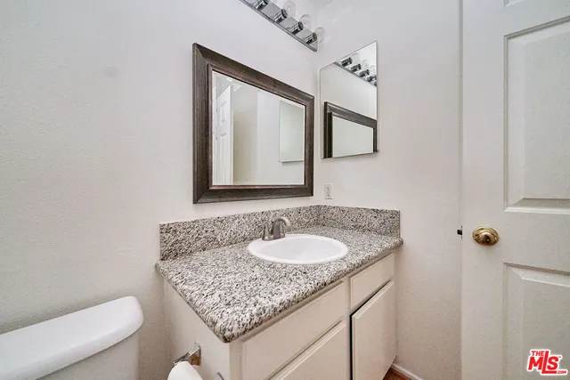 a bathroom with a granite countertop sink and a mirror