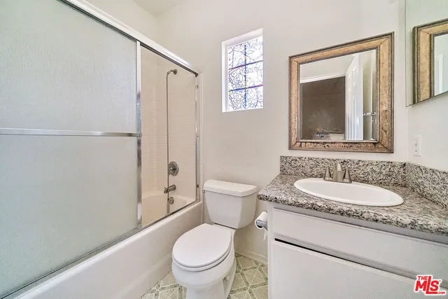 a bathroom with a granite countertop toilet sink and mirror