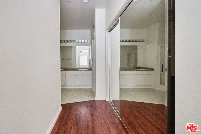 a view of a hallway with wooden floor and a kitchen space