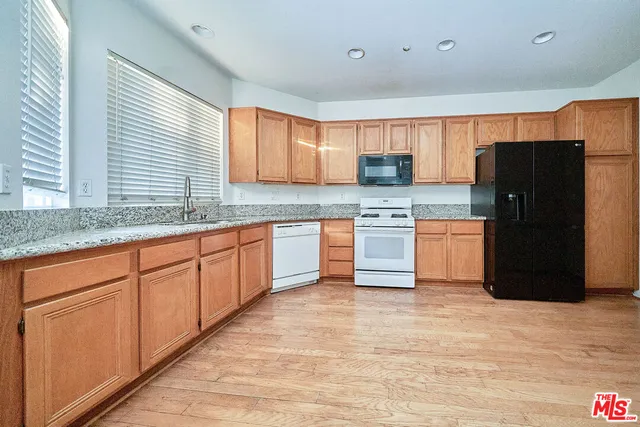 a kitchen with stainless steel appliances granite countertop a refrigerator a sink a stove with wooden cabinets