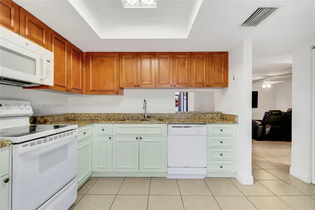 a kitchen with granite countertop white cabinets and white appliances