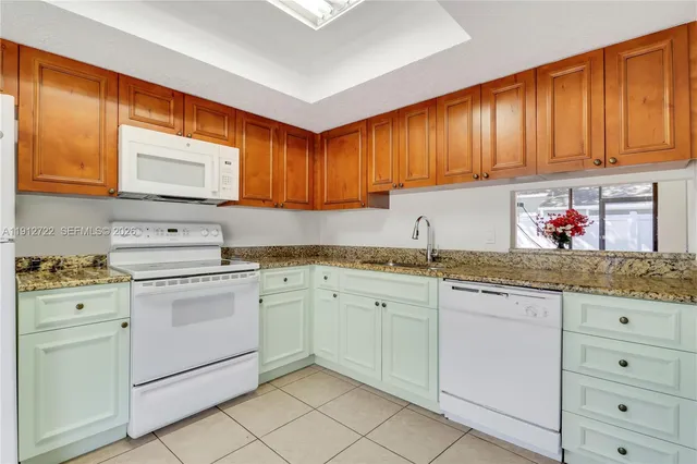 a kitchen with granite countertop cabinets sink and white appliances