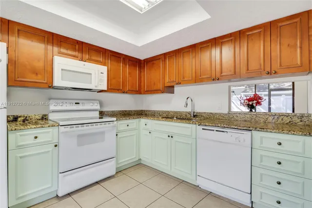 a kitchen with granite countertop cabinets sink and white appliances