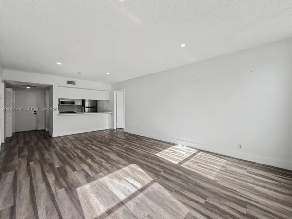 a view of kitchen and empty room with wooden floor
