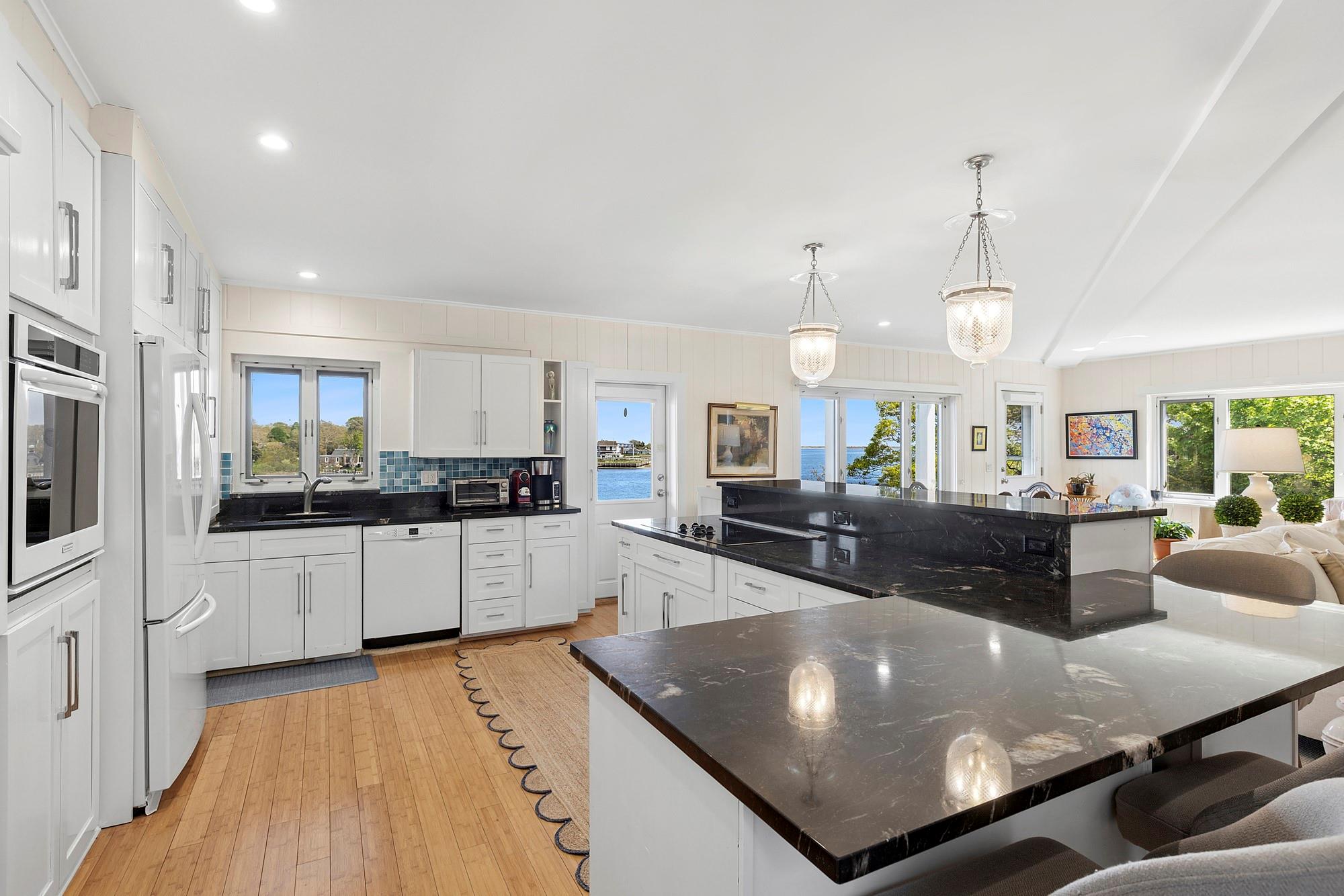 a large kitchen with kitchen island a large counter top stainless steel appliances and cabinets