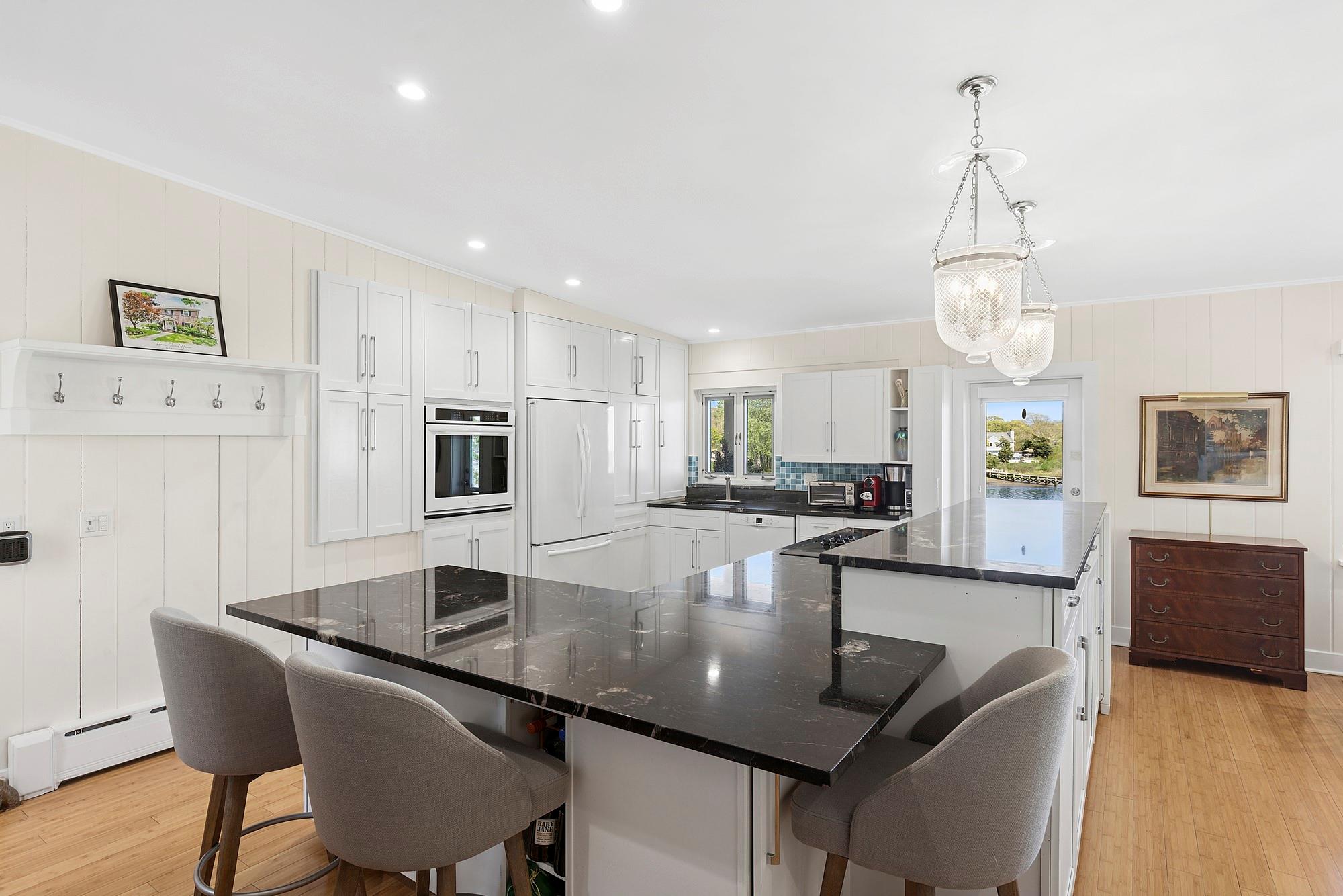 47 Rampasture Road, Unit M Hampton Bays, NY 11946 - Photo 6 of 17 a kitchen with granite countertop a table and chairs in it