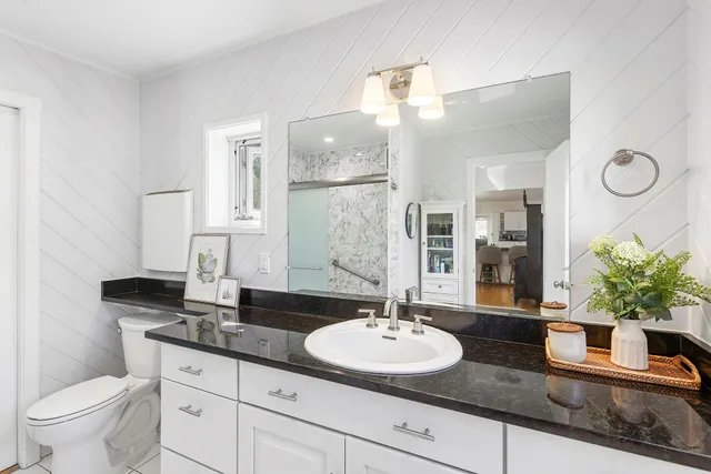 a bathroom with a granite countertop sink a toilet and a mirror