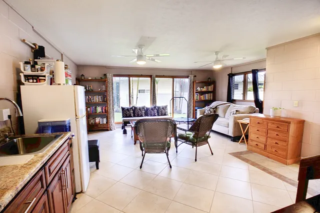 a living room with furniture a flat screen tv and a refrigerator