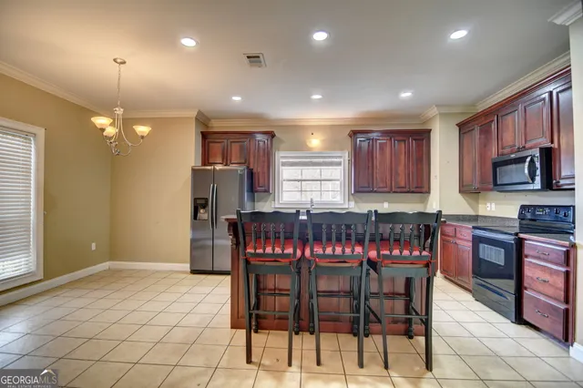 a kitchen with stainless steel appliances granite countertop a stove a sink a dining table and chairs