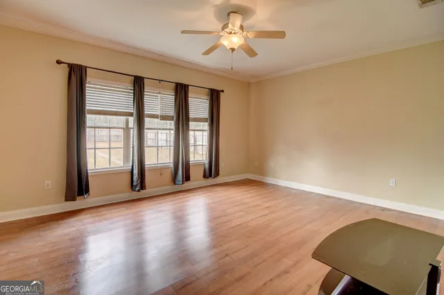 a view of an empty room with a window and wooden floor