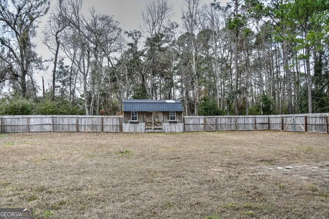 a view of a yard with wooden fence and trees