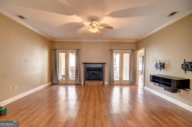 an empty room with wooden floor fireplace and windows