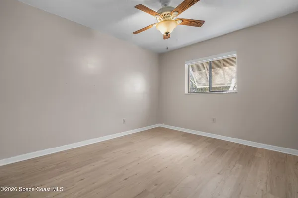 a view of an empty room with a window and wooden floor