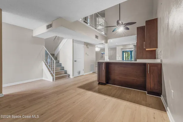 an empty room with wooden floor ceiling fan and windows