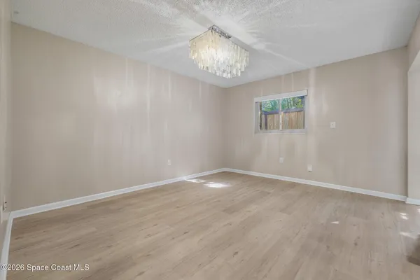 a view of an empty room with a chandelier fan