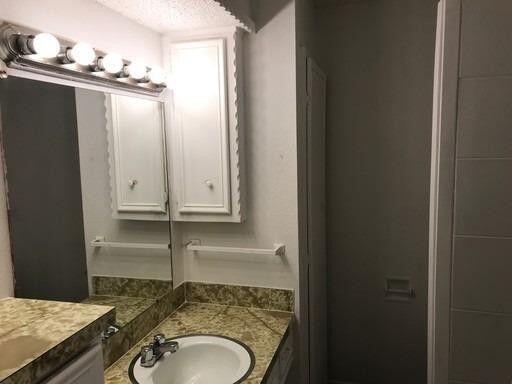1609 38th Street Lubbock, TX 79412 - Photo 7 of 8 a bathroom with a granite countertop sink and mirror