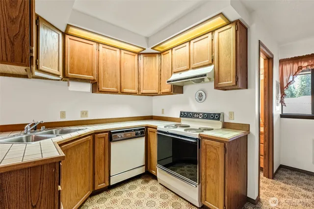 a kitchen with stainless steel appliances granite countertop a sink a stove and a microwave oven with cabinets