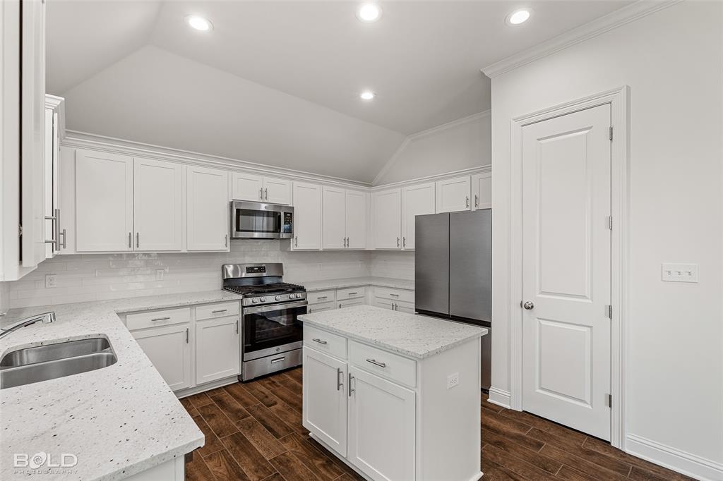 304 Prien Lk Loop Bossier City, LA 71111 - Photo 16 of 39 Kitchen featuring white cabinetry, stainless steel appliances, speckled countertops, a center island, and wood-finish flooring