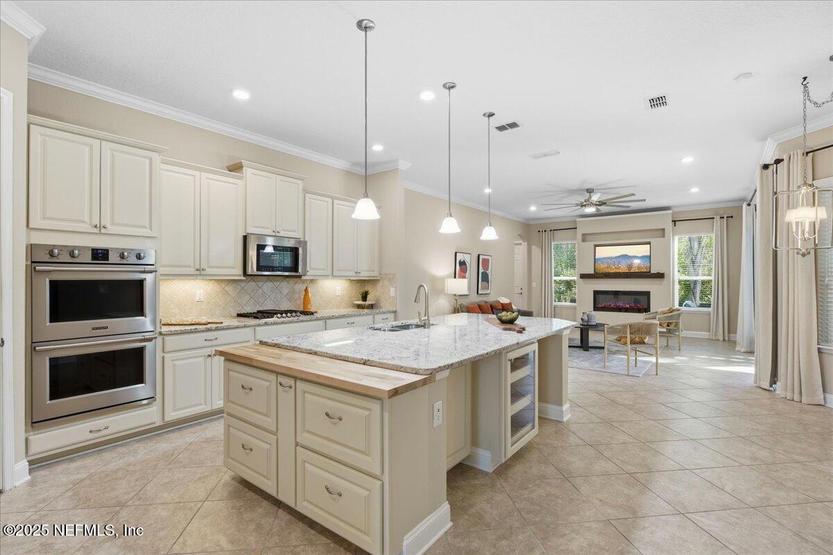 483 St Kitts Loop St. Augustine, FL 32092 - Photo 15 of 52 a kitchen with kitchen island a stove a sink a oven and a view of living room
