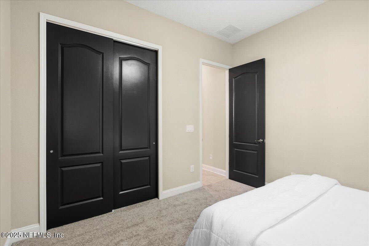 483 St Kitts Loop St. Augustine, FL 32092 - Photo 21 of 52 a bedroom with a bed and a mirror