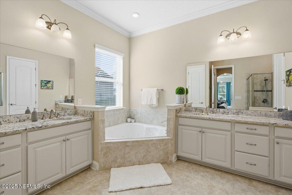 483 St Kitts Loop St. Augustine, FL 32092 - Photo 25 of 52 a spacious bathroom with a granite countertop double vanity sink a mirror a bathtub and window