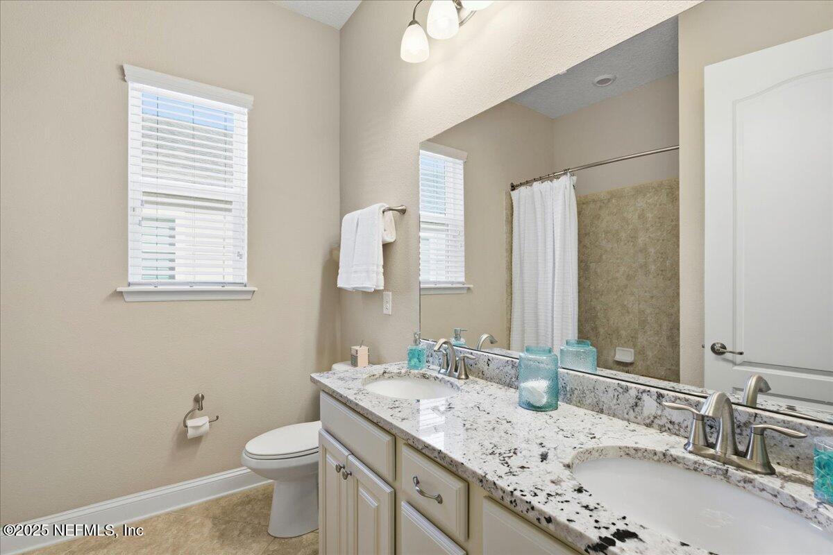 483 St Kitts Loop St. Augustine, FL 32092 - Photo 30 of 52 a bathroom with a granite countertop sink a mirror and a toilet