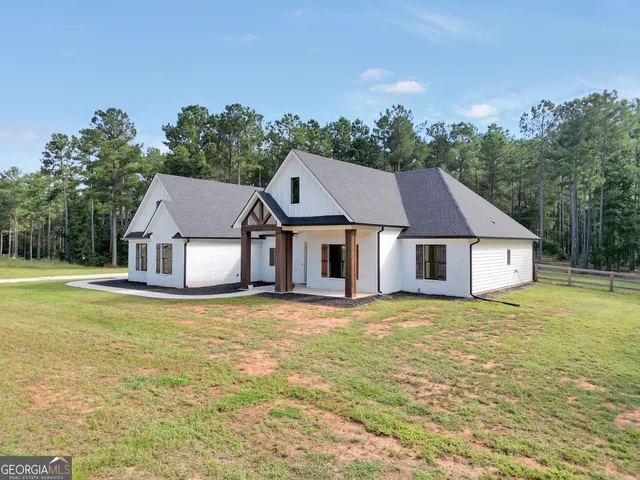 a view of house with yard and trees in the background