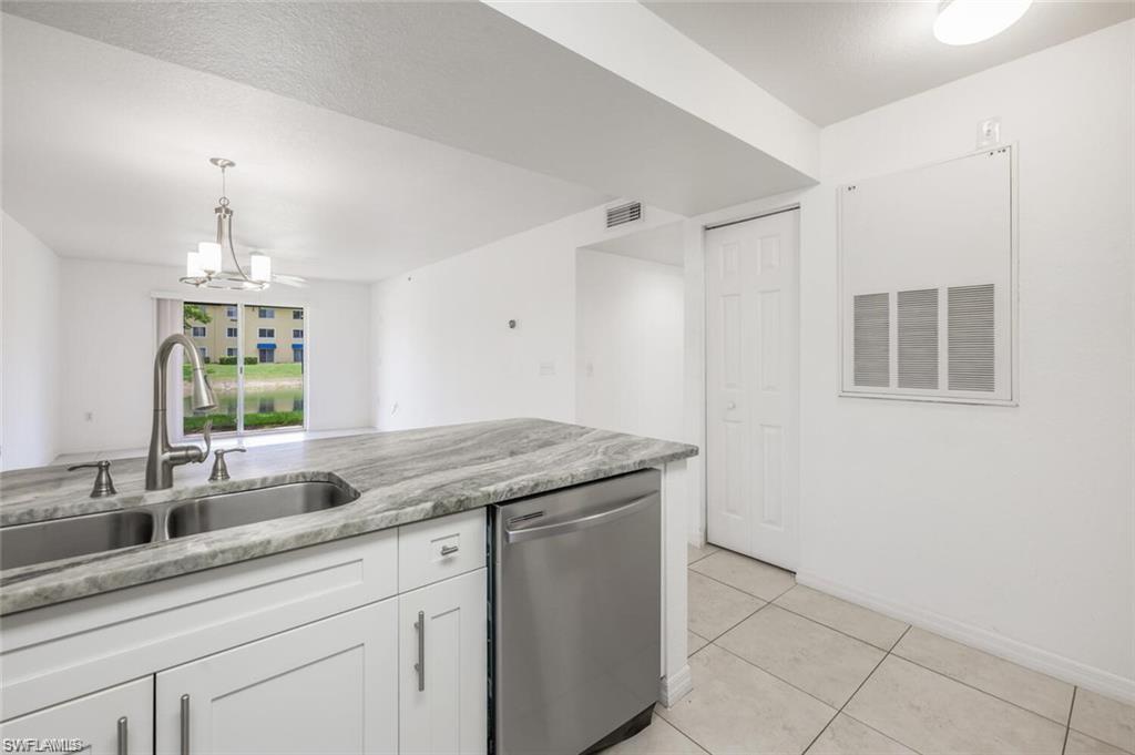 8244 Key Royal Circle, Unit 615 Naples, FL 34119 - Photo 5 of 23 Kitchen with white cabinets, dishwasher, light tile patterned floors, light stone counters, and decorative light fixtures