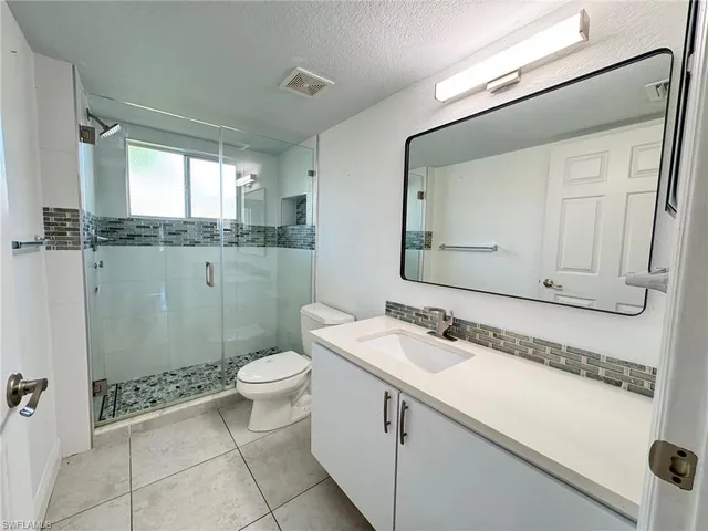 a bathroom with a granite countertop sink a toilet and a mirror