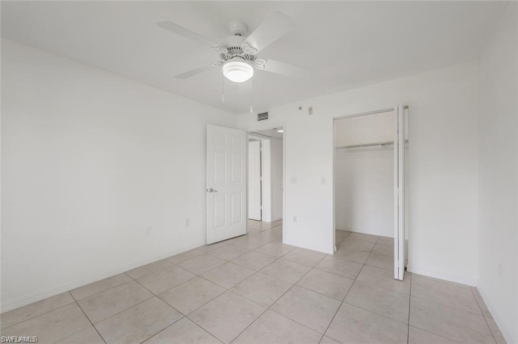 8244 Key Royal Circle, Unit 615 Naples, FL 34119 - Photo 8 of 23 Unfurnished bedroom featuring a ceiling fan, light tile patterned floors, and a closet