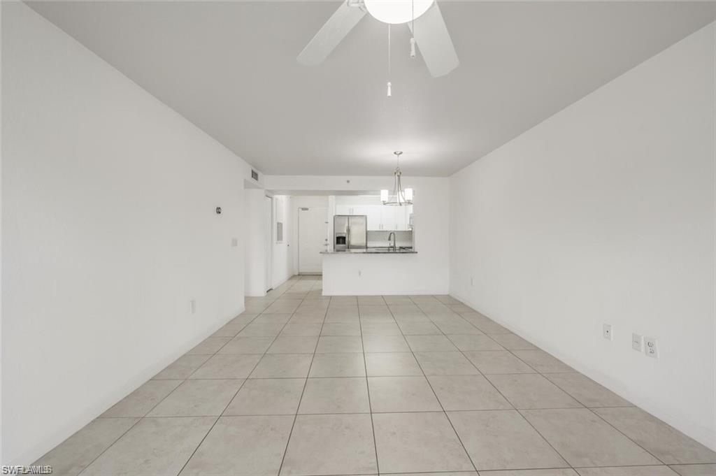 8244 Key Royal Circle, Unit 615 Naples, FL 34119 - Photo 10 of 23 Unfurnished living room featuring light tile patterned flooring, a ceiling fan, and a chandelier