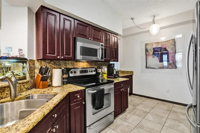 a kitchen with stainless steel appliances granite countertop a stove a sink and a microwave