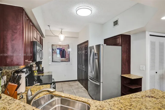 a kitchen with stainless steel appliances kitchen island granite countertop a refrigerator and a sink