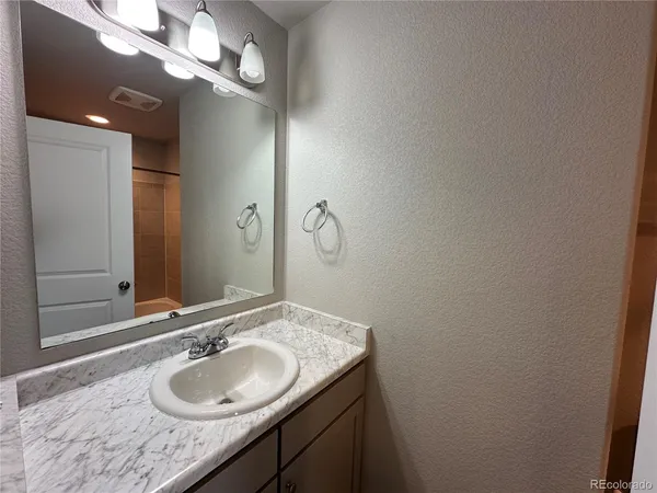 a bathroom with a granite countertop sink a light fixture and a mirror