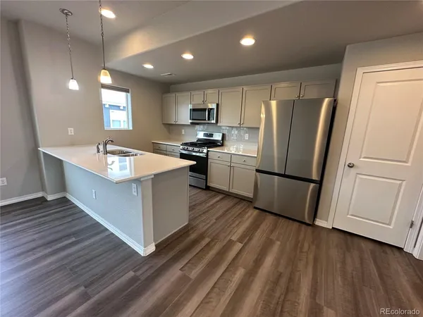 a large kitchen with stainless steel appliances granite countertop a lot of cabinets and wooden floor