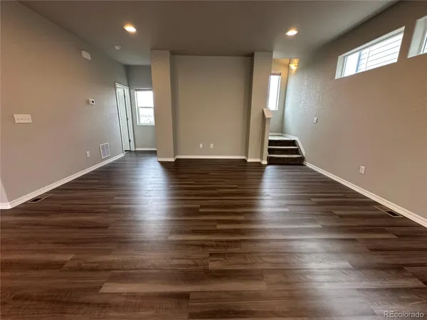 an empty room with wooden floor and windows