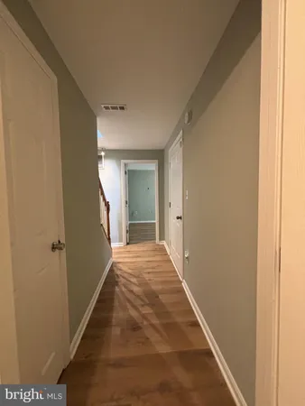 a view of a hallway with wooden floor and a bathroom
