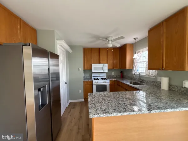 a kitchen with stainless steel appliances granite countertop a refrigerator a stove and a sink with wooden cabinets