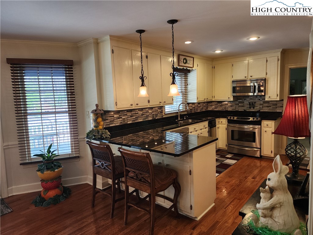 305 Old Farms Road Wilkesboro, NC 28697 - Photo 22 of 50 a kitchen with a table chairs stove and cabinets