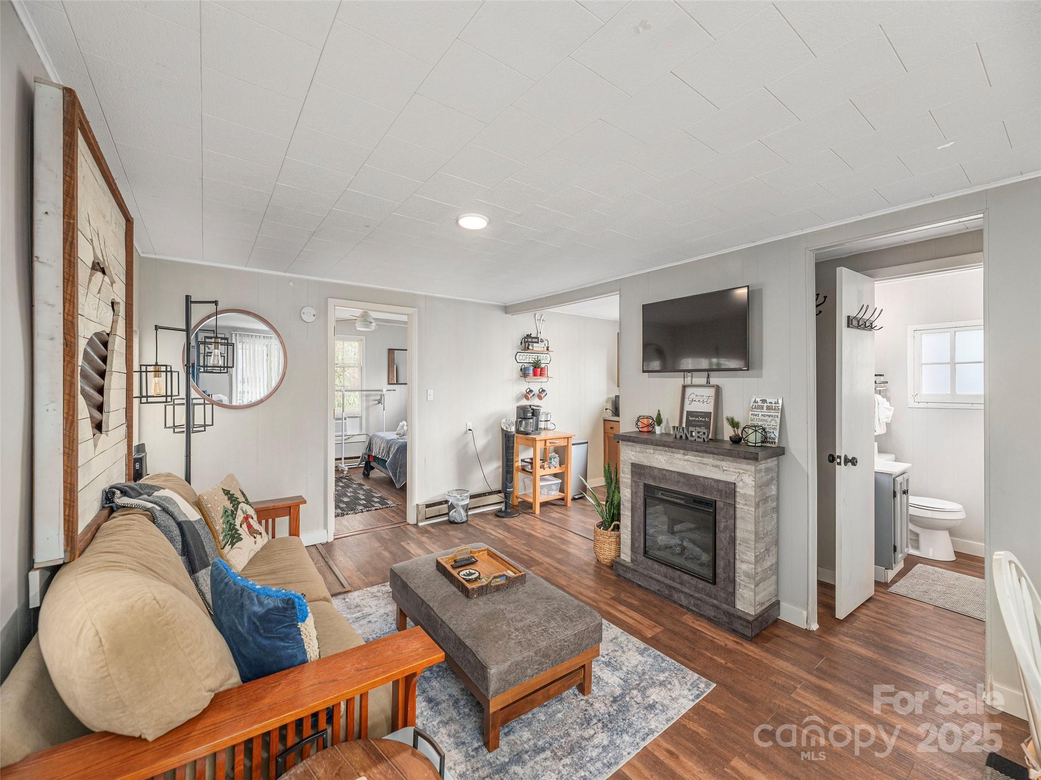 155 Mull Cove Road Maggie Valley, NC 28751 - Photo 3 of 19 a living room with furniture a fireplace and a flat screen tv