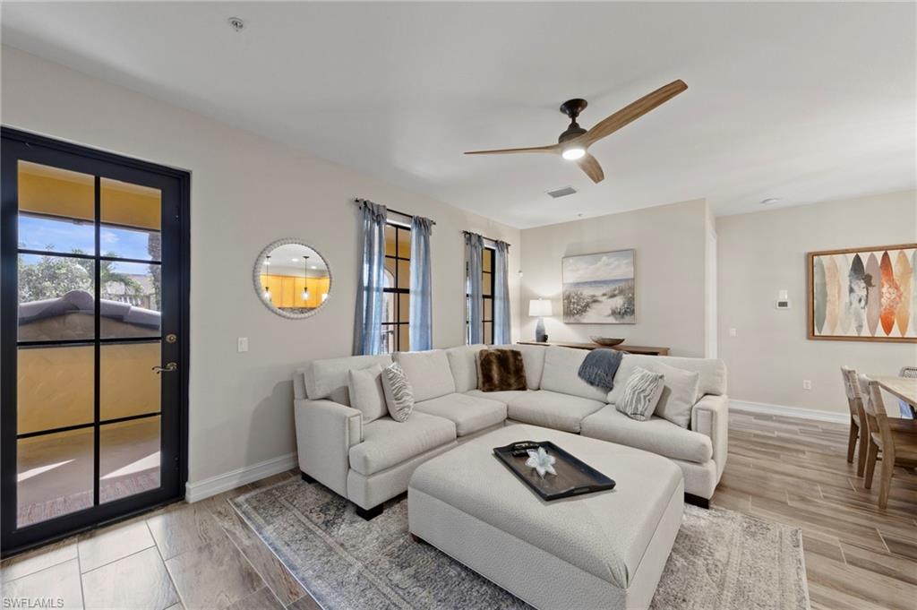 9076 Rialto Street, Unit 6204 Naples, FL 34113 - Photo 8 of 50 Living area featuring wood-finish tile flooring, a dark-framed glass paneled door, and a modern ceiling fan. NEW TILE FLOOR (2018)