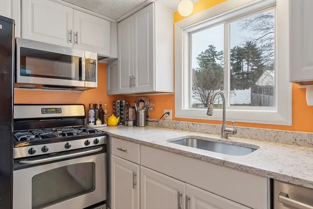 a kitchen with granite countertop a sink cabinets stainless steel appliances and a window