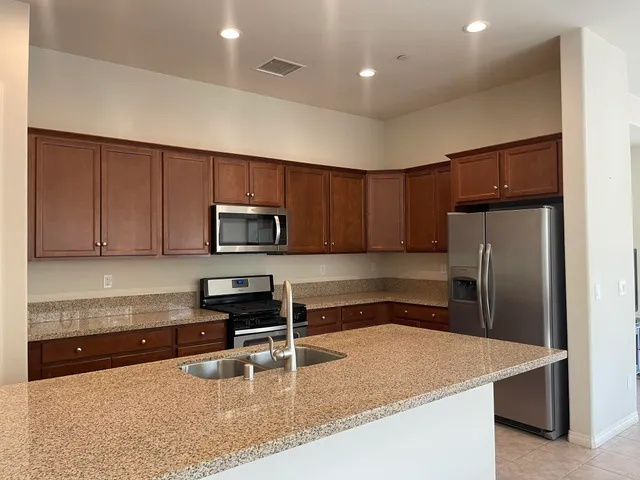 a kitchen with granite countertop a refrigerator a stove a sink a washer and cabinets