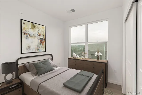 a bedroom with a bed painting on wall and a large window