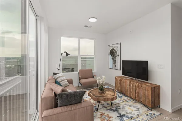 a living room with furniture a flat screen tv and a floor to ceiling window