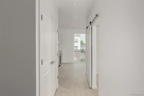 a view of a hallway with wooden floor and a bathroom